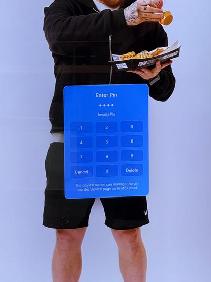 a closer look at the display shows that the man’s crotch is covered up by a blue “Enter Pin” dialog, with a keypad and text “The device owner can manage the pin via the Device page on Proto Cloud”