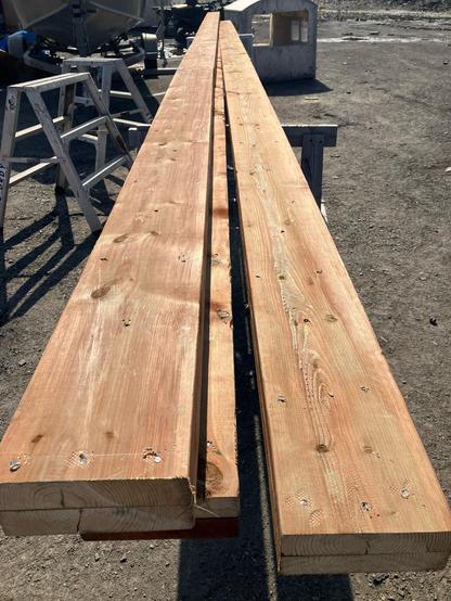 Three beams made of two plies of 2x8s, 28 feet long sit on saw horses.