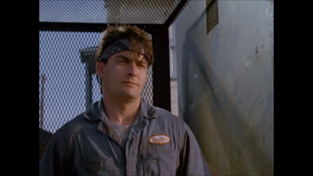 Clip from "Men at Work". One worker (played by Charlie Sheen) suggests a "golf clap" to the other (played by Emilio Estevez). The camera shows each speaker's head and shoulders as he speaks. The shot then widens to include two police officers. The workers give them a "golf clap" - leaning slightly forward from the waist, arms fully extended in front, palms touching and tilted to the left, hands flapping open and closed like a ducks bill to produce a polite little clap. The officers are suitably chastened. The action takes place in what seems to be  a parking lot, beside a garbage truck. The speakers are wearing blue-grey overalls and heavy gloves. The officers are wearing white short-sleeved collared shirts and dark shorts and appear to have arrived on bicycles. Each is holding a truncheon. The sky in the background is cloudless and blue on a bright day.
