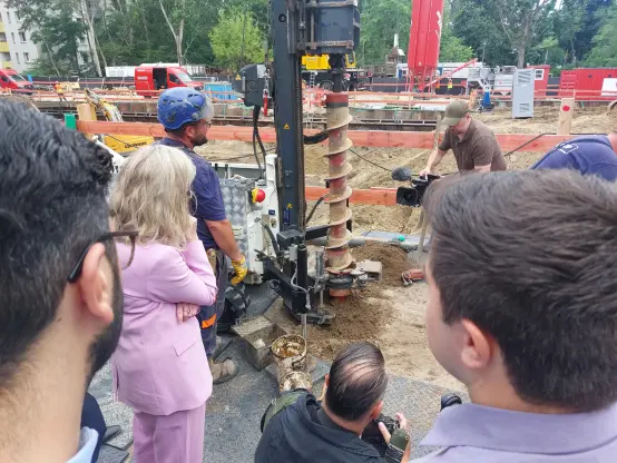 Menschen umringen einen Erdbohrer auf einer Baustelle.