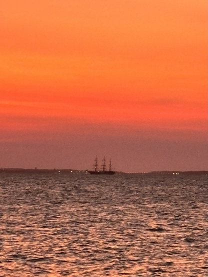 Romanian tall ship with a vibrant orange sky at sunset on the Chesapeake bay