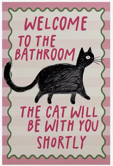 A decorative sign with a pink and white striped background and a wavy green border. It features a simple, hand-drawn black cat walking across the center. The text, written in pink playful lettering, reads: "WELCOME TO THE BATHROOM" at the top and "THE CAT WILL BE WITH YOU SHORTLY" at the bottom.