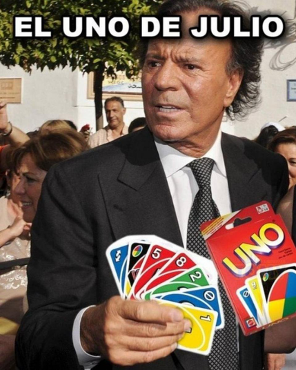Sunny outdoor photo of Julio Iglesias with his hands out. Someone has photo edited a box and hand of cards in both for the game Uno. Top text reads "El Uno de Julio"