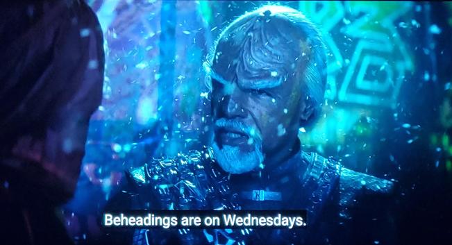 Star Trek Picard scene. An older Worf is shown, white eyebrows and goatee. There's a 'Mr. Worf Goes to a Rave' feel, with what looks like confetti dropping over him, blacklighting, and abstract art on the walls behind him, presumably drawn in Tide.  Closed caption reads, "Beheadings are on Wednesdays."