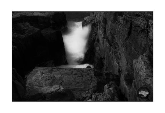A small sea canyon filled with waves. Monochrome.