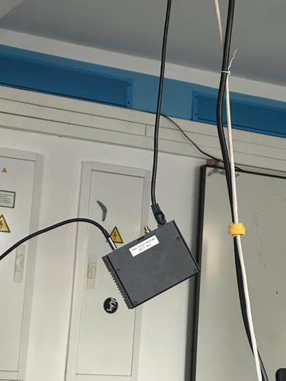 Man sieht einen Mini PC welcher mit einem LAN Kabel von der Decke baumelt