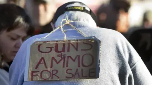 "Cardboard, twine, and a marker. No table, no license, no way to check who's buying. A private seller works the crowd at the Crossroads of the West show in Phoenix — the legal transaction this piece is about. Photo: Cheryl Evans/The Arizona Republic."