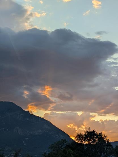 Le ciel en feu au soleil couchant.
A gauche une montagne qui laisse filer quelques rayons orangés.

Au centre, le ciel orangé qui semble brûler.

En haut, des nuages qui font ressortir les rayons lumineux.