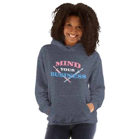 Smiling woman wearing a blue grey hoodie with a “mind your business” design featuring stylized topography and crossed swords – in trans flag colors.