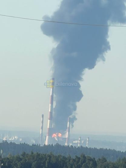 A plume of black smoke rises from a burning refinery