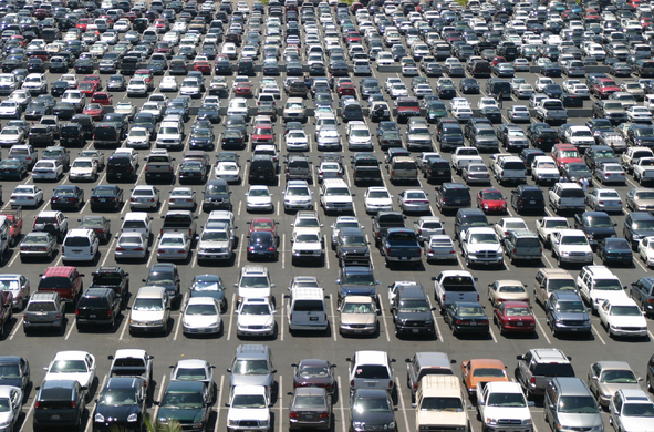 A big above-ground parking lot with parked cars as far as the eye can see.