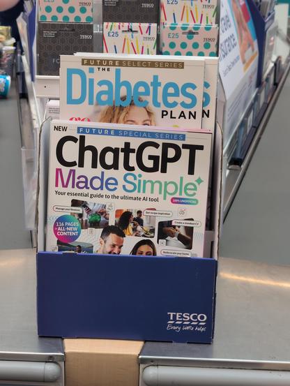 A magazine rack, branded Tesco. One of called "ChatGPT made simple". The one above it is "The Diabetes Plan"