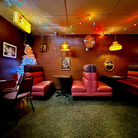 Corner of a dive bar with dark burnt orange vinyl booths and a Christmas tree even though it's summer time.