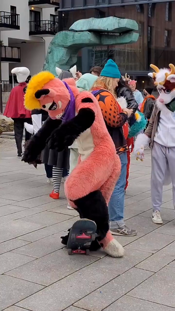 A furry in a pink fur suit with a yellow mohawk doing a kickflip on a skateboard before rolling down a bunch of stairs