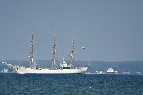 Tall ship sailing on the Chesapeake bay the Thomas Point Lighthouse in the distance.