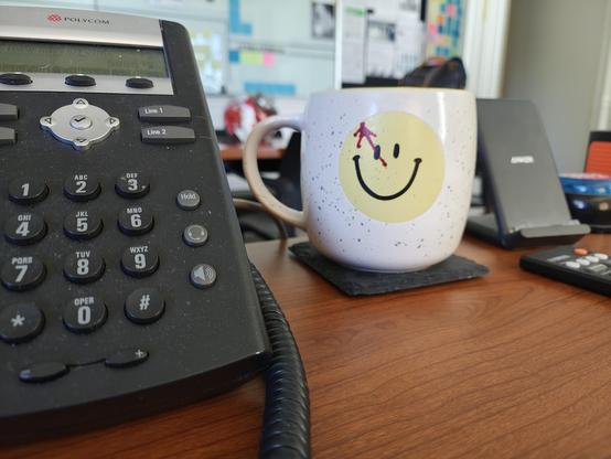 Mug, with a smile face on it. On the smile face, in the upper left, is a red splatter of what looks like blood.