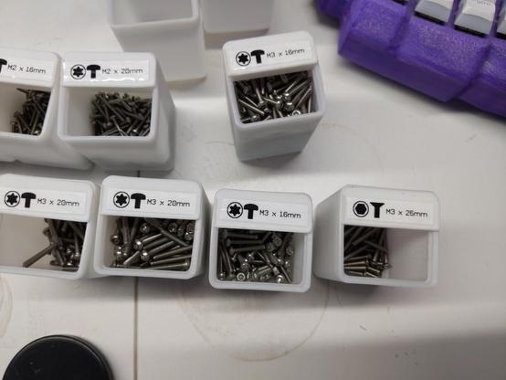 a bunch of boxes with screws in them. each one has a label on top with icons for drive type and head shape, then text like "M3 x 20mm"