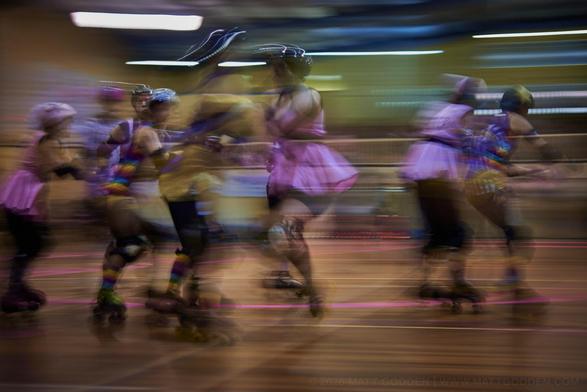 A long exposure image of roller derby competitors from the Beauty School Knockouts (pink), and Team Unicorn (Purple & Gold). 2013/11/09