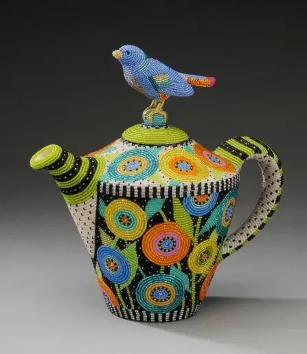 Bead covered teapot with floral design and bird perched on the lid