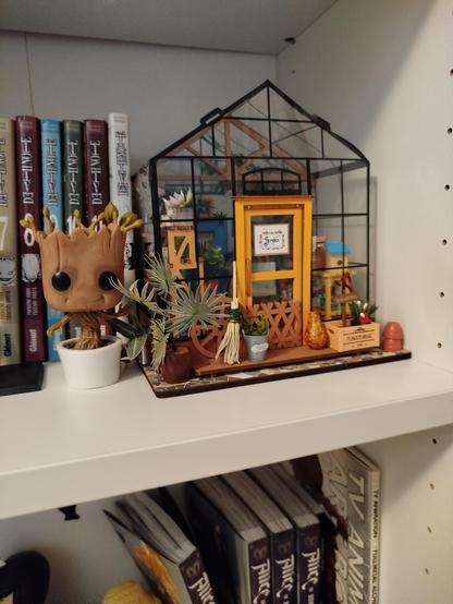 La maqueta del toot anterior puesta en la balda de una librería de color blanco, junto a unos mangas de Death Note y un funko de Groot de Guardianes de la galaxia.