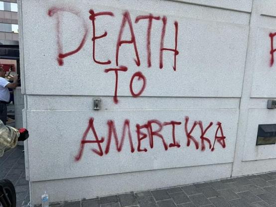 A wall spray painted with rough graffiti that says "Death to Amerikka."
