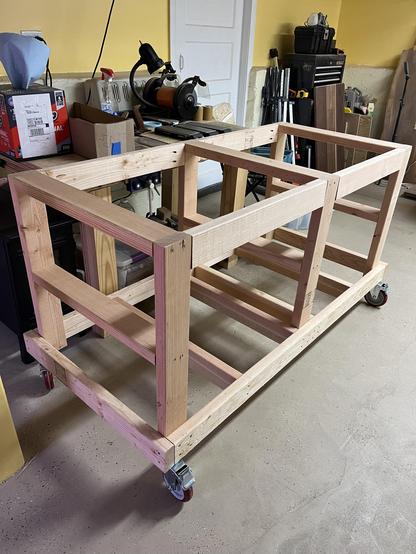 A wooden cart made of a number of 2x4's. It has large casters for wheels. It's large enough to hold and move a wood cabinet.