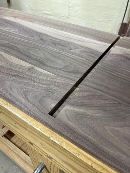 A dado joint across the interior of a walnut cabinet wall.