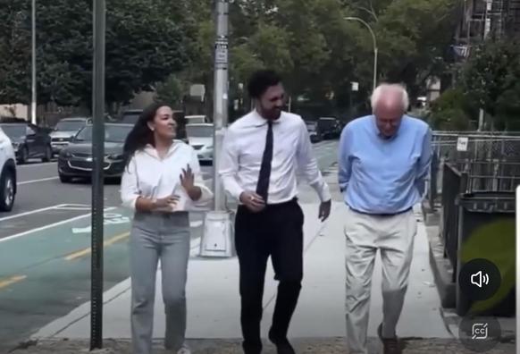AOC, Zohran Mamdani, and Bernie Sanders walking a sidewalk