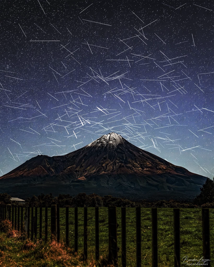 Night time photo of Mt Taranaki. The sky has hundreds of short white streaks crisscrossing. Taken by Brendan Larsen