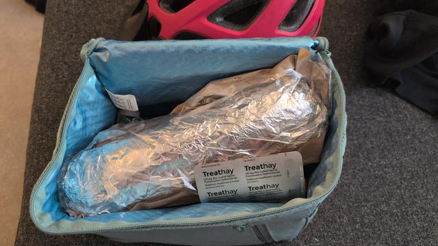 A big foil wrapped baton/sub style sandwich stretches out a small cool bag diagonally. Looks like it might be difficult to zip up