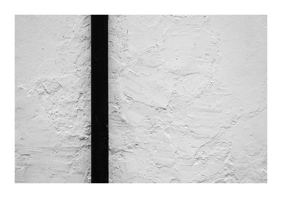 An old white textured wall with a black drainpipe.