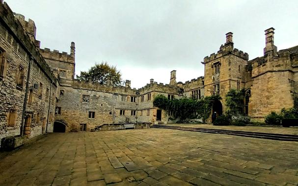 The lower courtyard at Haddon Hall. To the left is a wall containing the chapel, administrative buildings and main entrance. To the right is the entrance to the living quarters including the Tudor kitchens and Great Hall.