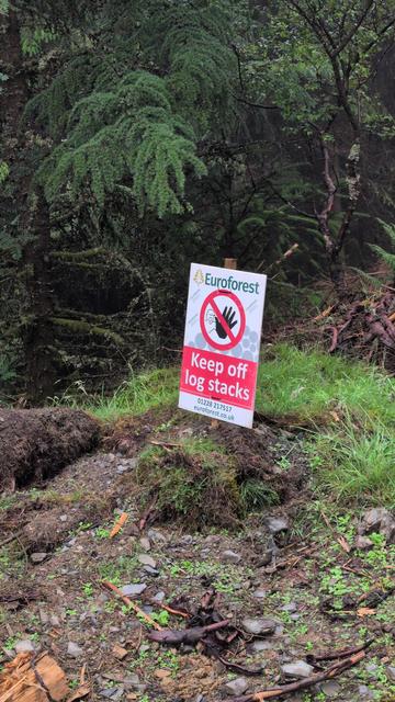 A sign in a forest says "euroforest keep off log stacks"