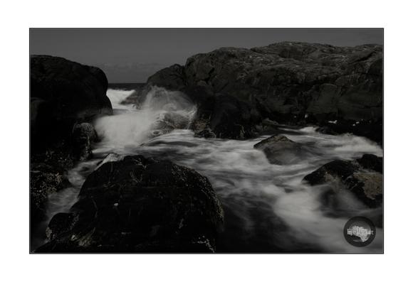 The waves between the rocks. Long exposure. Monochrome.