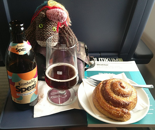 Max, das bunte Strickhorn, mit Spezi und Zimtschnecke im Zug.