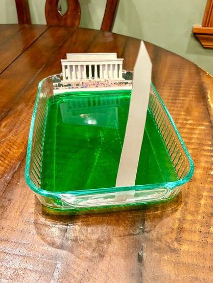 Livid green jello in a clear rectangular Pyrex dish, with cutouts of the Lincoln Memorial and Washington Monument at either end.