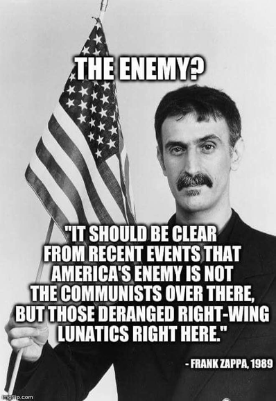 Man holding an American flag with quote: "The enemy? It should be clear from recent events that America's enemy is not the communists over there, but right-wing lunatics here." - Frank Zappa, 1989.