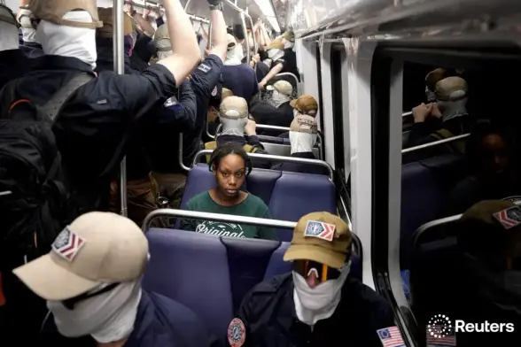 A Washington DC subway car full of Patriot Front fascists with face coverings and matching uniforms and one black woman giving a side eye to the whole car looking in the general direction of the camera.
Picture by Cheney Orr credited to Reuters.