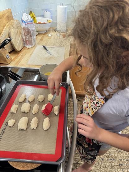 Ērika painting egg yolk on pīrāgi we’re baking