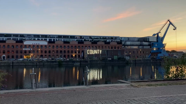 Movie clip showing large white segmented alphanumeric display on the side of an industrial building, reflected in a canal. the sign displays “COUNTY: BUTTE / OUT:  1 / CAUSE: UNKNOWN”