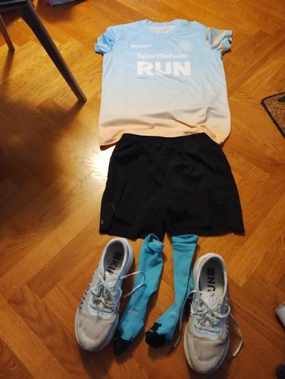 Kit layout on the floor. Pale t-shirt, black shorts,. turquoise socks, white shoes.