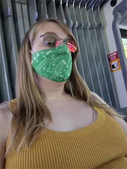 me sitting in the bendy part in the middle of the bus. I'm starting this nice orange knit tank top and a circuit print mask.