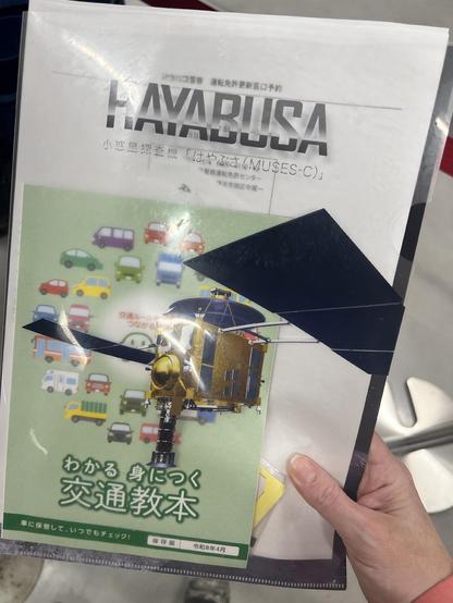Driving license documents in a clear file with a picture of the first Hayabusa spacecraft on the front.