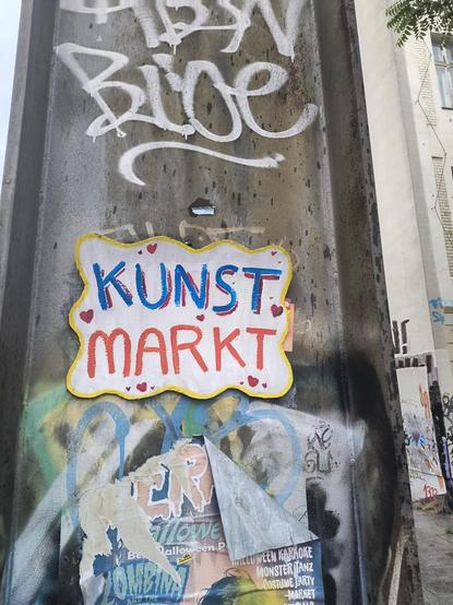Ein Schild "Kunst Markt" aus einen Pfeiler, eingerahmt von Graffiti