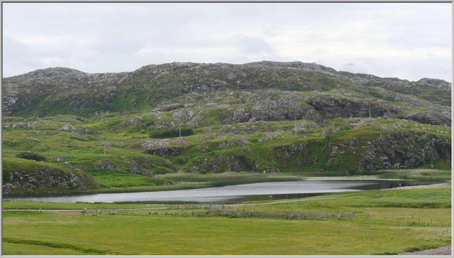 A delightful little loch, with steeply rising rocky hiillsides beyond, rising to a small hill eventually. Somewhere in there is The Last Homely House