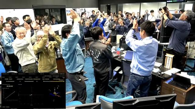 Screen shot from the live feed, showing the Hayabusa2 control room where everyone is giving a celebratory high-five!