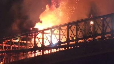 Photo of flames leaping from a section of the Brooklyn Bridge, in the dead of night.
