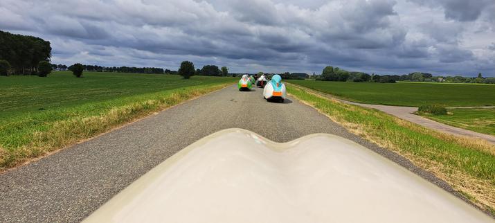 Velomobielen in een rijtje achter elkaar op een dijk langs de IJssel.