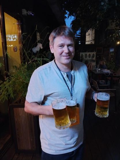 Man carrying three (3) beers.