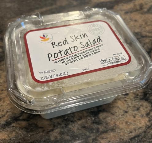 Photo of a 1 pint plastic container that sells red skin potato salad and in the container you can see the white mushy potato salad